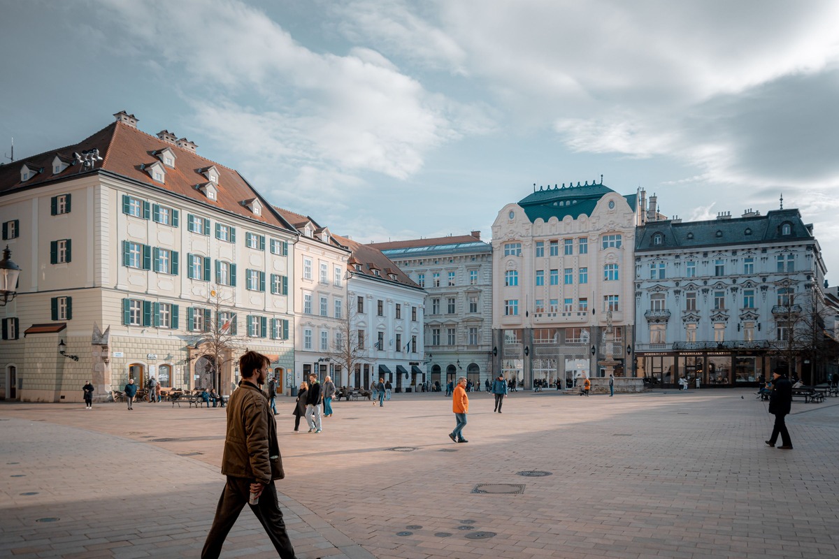 A city main square in Bratislava, a man walking across the paving in the foreground on the left